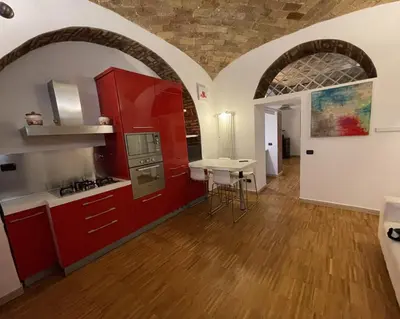 a kitchen with red cabinets and a table in a room at Heart of San Lorenzo - La casa particular in Rome