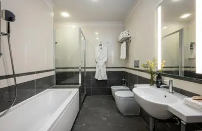 a bathroom with a bath tub and a sink and a robe at Leonardo Boutique Hotel Rome Monti in Rome