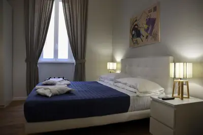 a bedroom with a bed with a blue blanket and two windows at The Castle Inside Rome in Rome