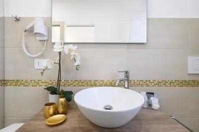 a bathroom with a white sink and a vase with flowers at La Meraviglia- San Pietro - Vatican Area in Rome