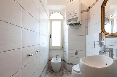 a white bathroom with a sink and a toilet at Kyterion Apartment in Rome