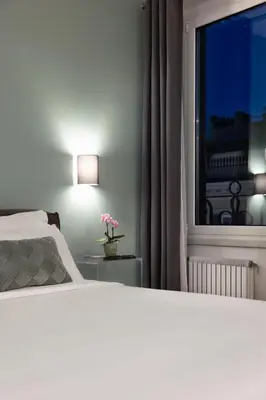 a bedroom with a bed and a window with a flower on a table at Fellini Design Suites in Rome