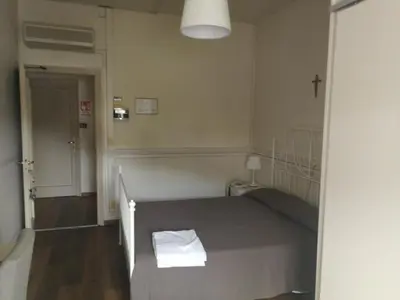 a bedroom with a bed with a cross on the wall at Casa per Ferie Suore Domenicane in Rome