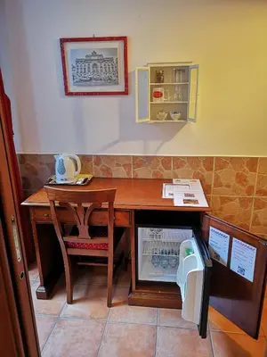 a room with a desk and a table with a refrigerator at Vecchia Roma Resort in Rome