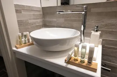 a bathroom counter with a bowl sink and cosmetics on it at Barcaccia Luxury Suites in Rome