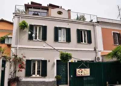 a white building with green doors and a fence at B&B Abbraccia Morfeo in Rome