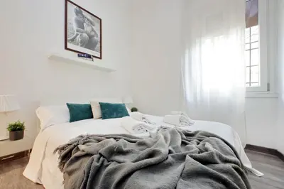 a white bedroom with a white bed with blue pillows at Scipioni Terrace in Rome