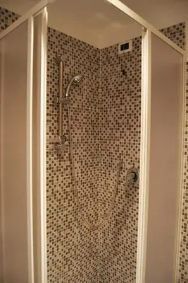 a shower in a bathroom with a tile wall at Core De Roma Suites in Rome