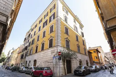 a yellow and white building on a street with parked cars at Emma's Apartment Borgo, Vatican City in Rome