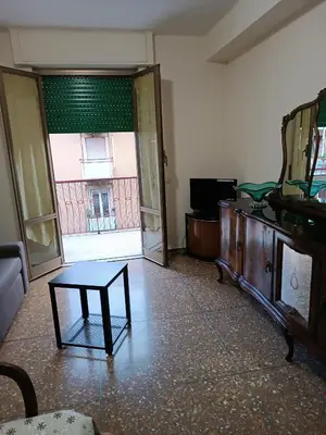 a living room with a couch and a table and a door at Hortis Apartment, 5 persone, 2 camere, balcone, Metro C per il Colosseo a 10 minuti e tram per Termini a 2 minuti in Rome
