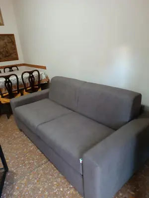 a gray couch in a living room with a table at Hortis Apartment, 5 persone, 2 camere, balcone, Metro C per il Colosseo a 10 minuti e tram per Termini a 2 minuti in Rome