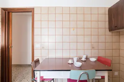 a kitchen with a table and chairs and a tiled wall at Hortis Apartment, 5 persone, 2 camere, balcone, Metro C per il Colosseo a 10 minuti e tram per Termini a 2 minuti in Rome