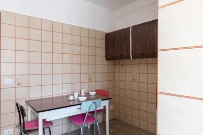 a kitchen with a table and two chairs and a refrigerator at Hortis Apartment, 5 persone, 2 camere, balcone, Metro C per il Colosseo a 10 minuti e tram per Termini a 2 minuti in Rome