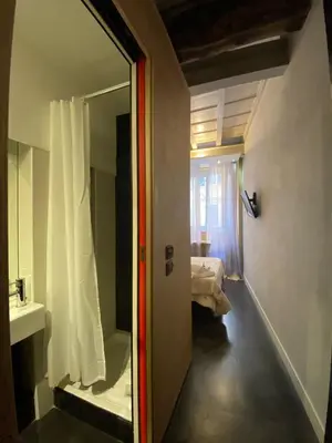 a bathroom with a mirror and a bed in a room at Nerva Accommodation in Rome