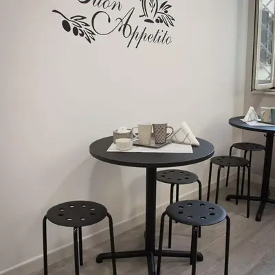 a table and stools in a room with a sign on the wall at VaticanArt in Rome
