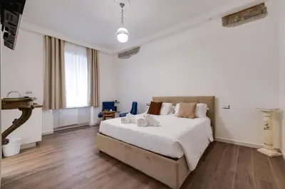 a bedroom with a bed with white sheets and wooden floors at Classic Flat Monti in Rome