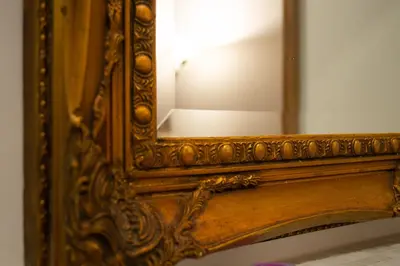 an ornate mirror with a wooden frame on a wall at Dillo Suites in Rome