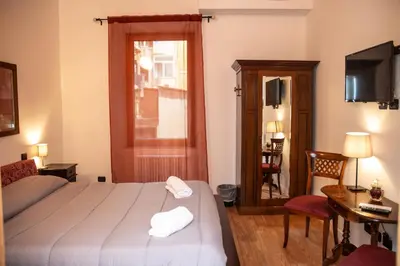 a bedroom with a bed and a desk and a television at Dillo Suites in Rome