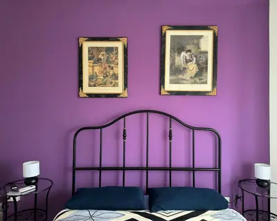 a bedroom with purple walls and a bed with two pictures at Bibbi's House San Lorenzo in Rome