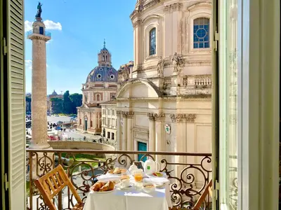 a table on a balcony with a view of a building at Colonna Traiana - The View Boutique Luxury Home in the center of ancient Rome in Rome