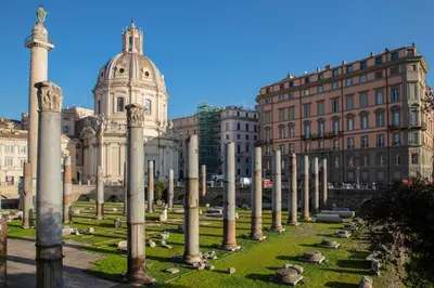 a row of columns in a park in front of buildings at Colonna Traiana - The View Boutique Luxury Home in the center of ancient Rome in Rome