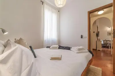 a bedroom with a bed with white sheets and a mirror at Lively Roma Trastevere renovated apartment - FromHometoRome in Rome