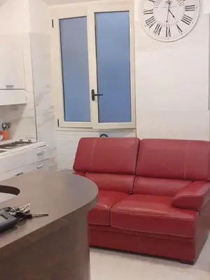 a red couch in a kitchen with a clock on the wall at ABID'S PALACE IN TERMINI in Rome