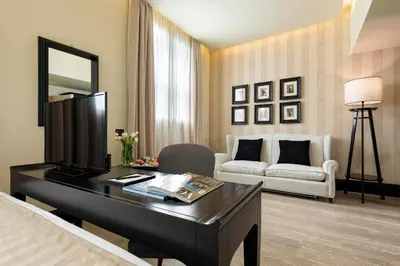 a bedroom with a desk with a television and a couch at Profumo Maison Colosseo in Rome
