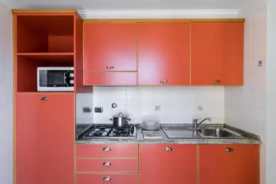 a kitchen with red cabinets and a stove and a sink at Crosti Apartments in Rome