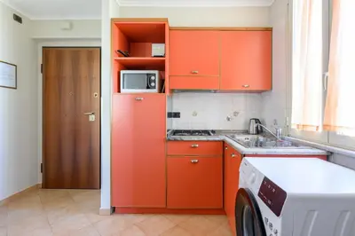 a kitchen with orange cabinets and a washing machine at Crosti Apartments in Rome