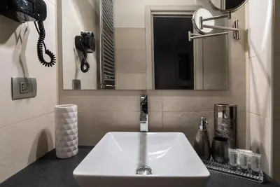 a bathroom with a white sink and a phone at Black And White Suite in Rome