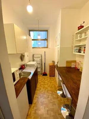 a kitchen with white cabinets and a wooden floor at la casa di Romolo in Rome