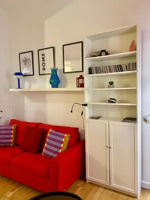 a living room with a red couch and a book shelf at la casa di Romolo in Rome
