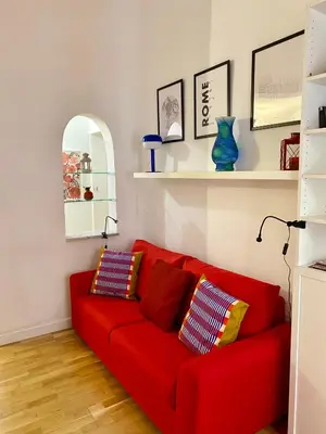 a red couch in a living room with a mirror at la casa di Romolo in Rome