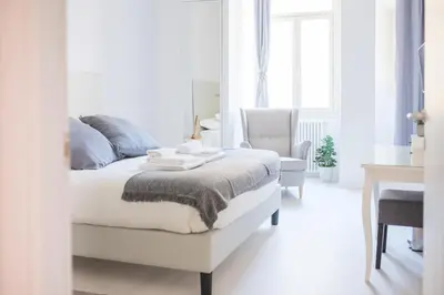 a white bedroom with a bed and a chair at White Fanti Apartment in Rome