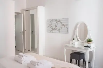 a white bedroom with a vanity and a mirror at White Fanti Apartment in Rome