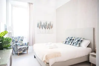 a white bedroom with a bed and a chair at White Fanti Apartment in Rome