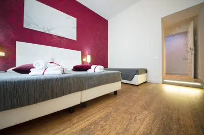 a bedroom with two beds and a red wall at Residenza Alexander Guest House in Rome