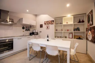 a white kitchen with a white table and chairs at Restart Accommodations Borghese in Rome