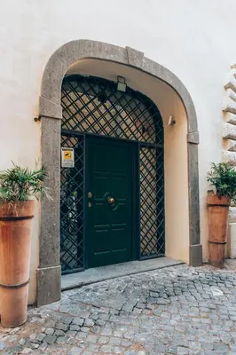 an archway with a green door and two potted plants at Restart Accommodations Borghese in Rome