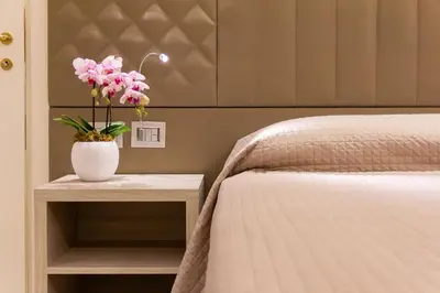a bedroom with a bed and a vase with flowers on a table at Harry's Bar Trevi Luxury Apartments - Spagna in Rome