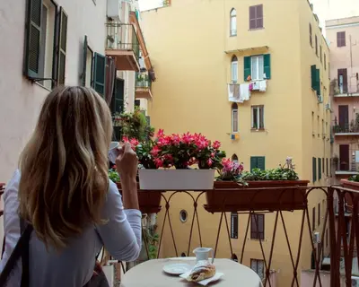 a woman standing on a balcony taking a picture of flowers at Domus Victoria Guest House in Rome