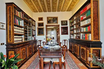 a dining room with a table and chairs and bookshelves at TreasureRome Daphne Terrace in Rome