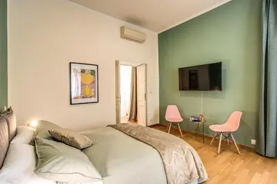 a bedroom with a bed and two pink chairs at Diocleziano Triple in Rome