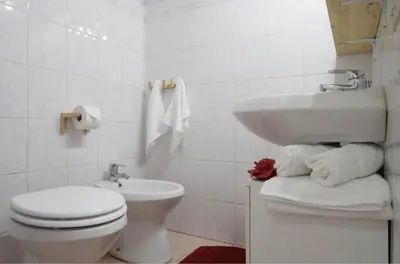 a white bathroom with a toilet and a sink at La casa di Remo in Rome