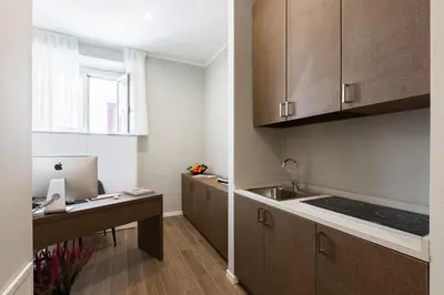 a kitchen with wooden cabinets and a sink and a desk at Giubbonari Suites in Rome