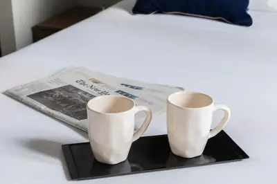 two white cups on a black tray next to a newspaper at Giubbonari Suites in Rome