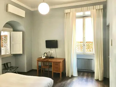 a bedroom with a bed and a desk with a television at B&B Santi Quattro Al Colosseo in Rome