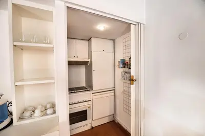 a small kitchen with white cabinets and a door at Appartamento via dei Baullari in Rome