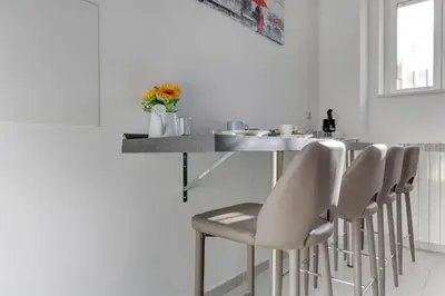 a kitchen with a bar with white stools at Voyager House Termini - Home and More in Rome